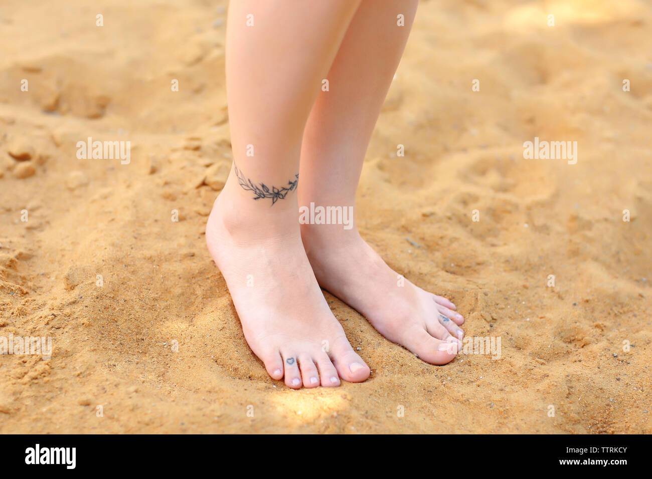 Female legs with tattoos on sand Stock Photo - Alamy