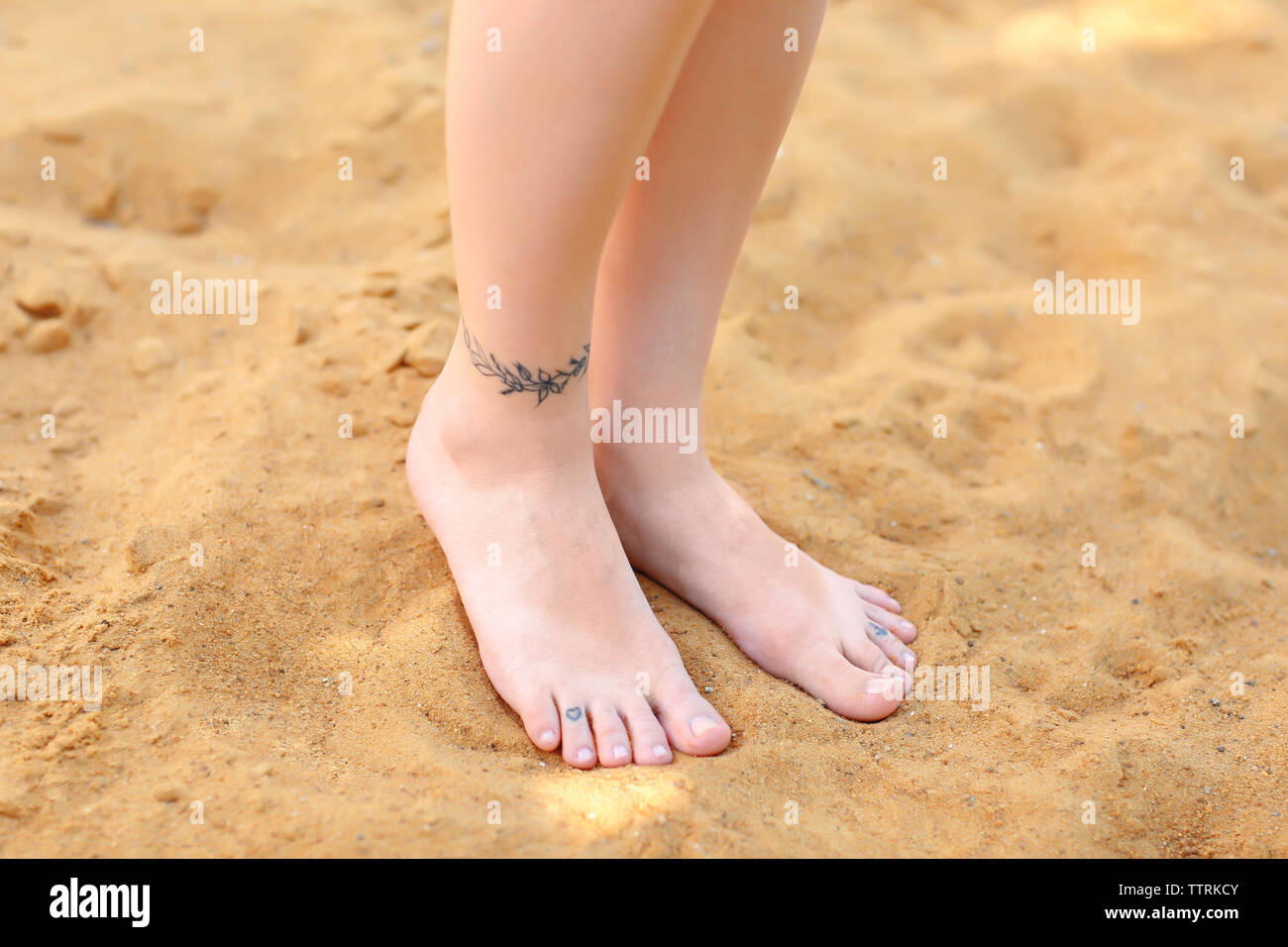 Female Legs With Tattoos On Sand Stock Photo Alamy