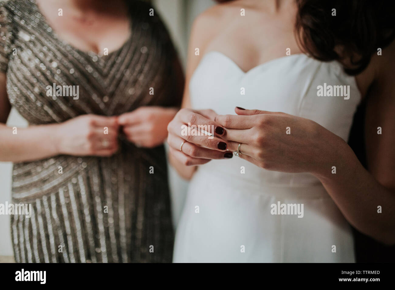 Midsection of bride wearing wedding dress while standing by bridesmaid Stock Photo