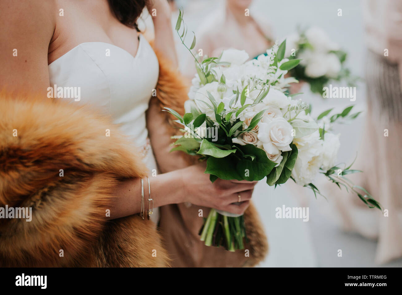 Midsection of bride with fur holding bouquet during wedding ceremony Stock Photo