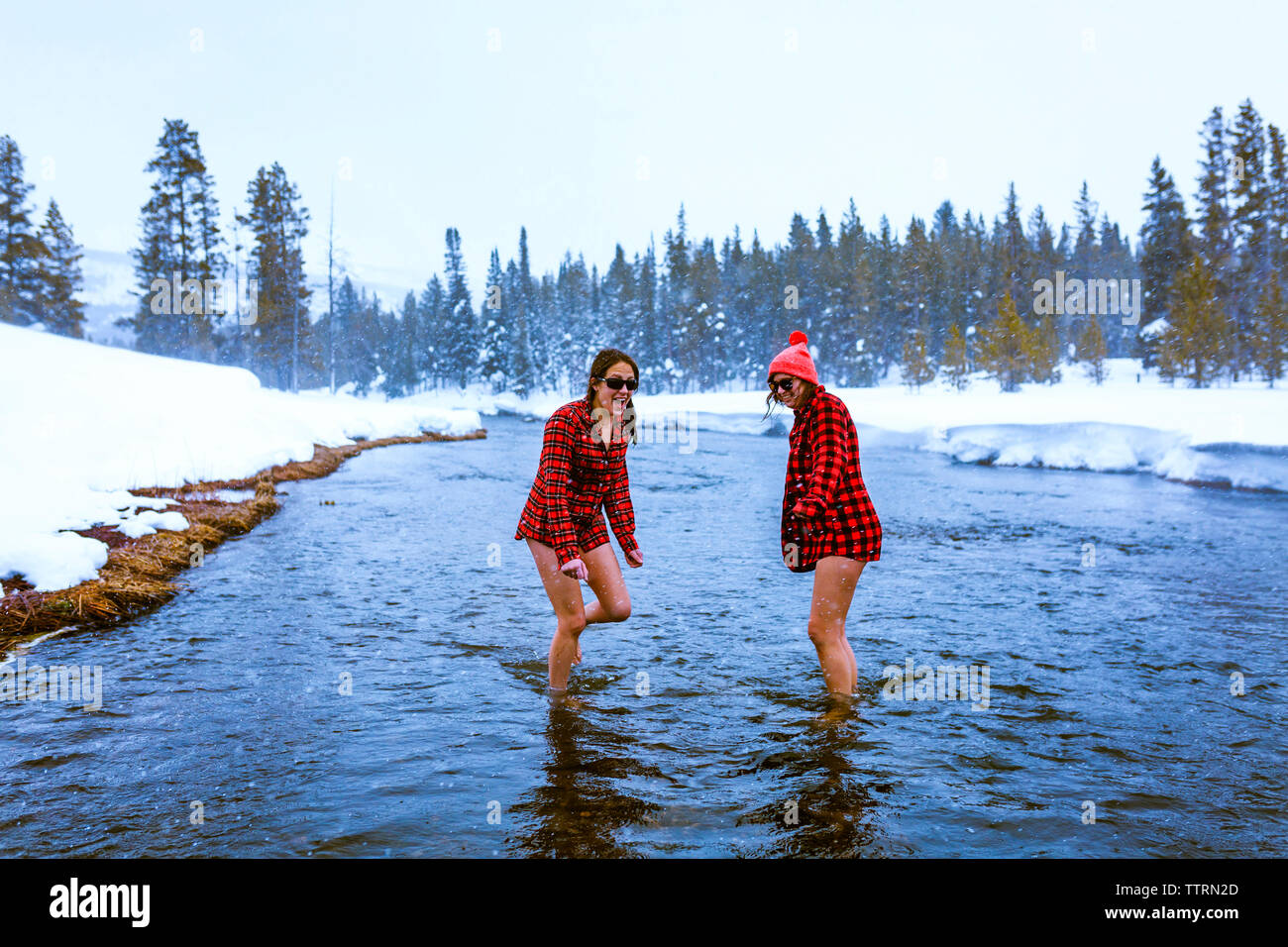 Female friends enjoying in lake against sky during winter Stock Photo