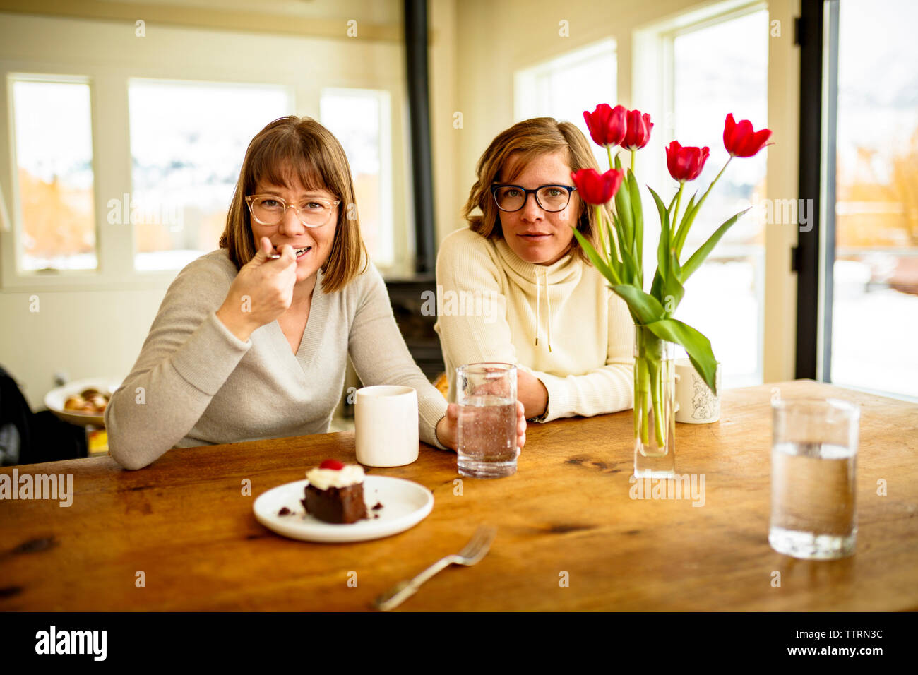 Portrait of sisters sitting at table Stock Photo - Alamy