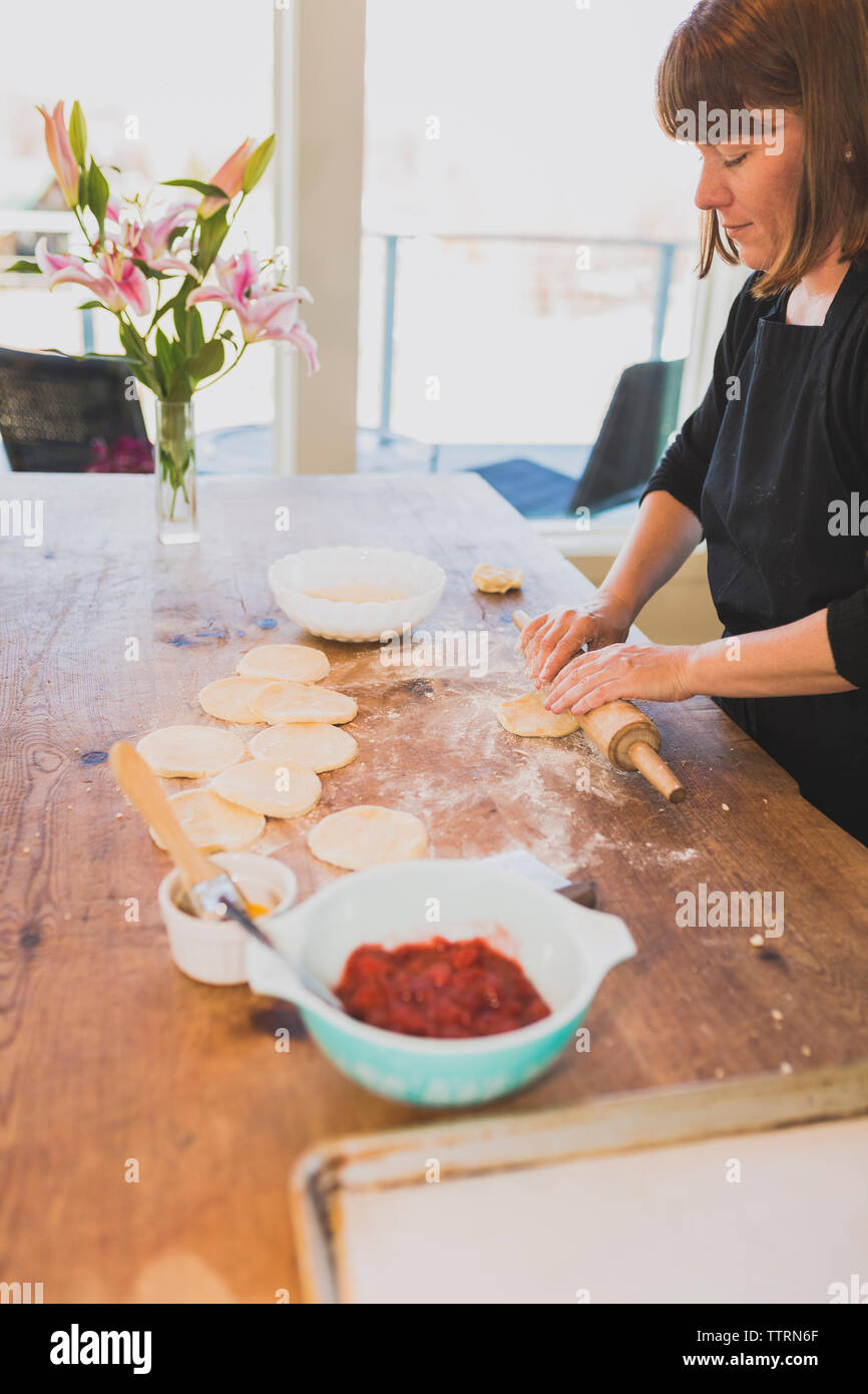 Woman rolling dough while preparing food at home Stock Photo