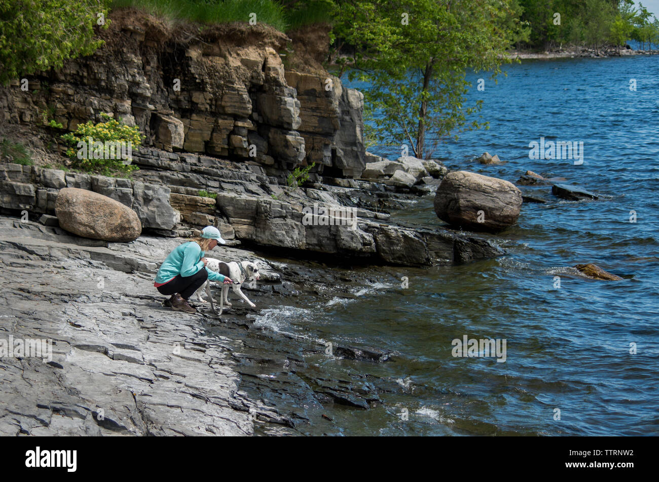 Female with dog on a lake shore trying to get close to the water Stock Photo