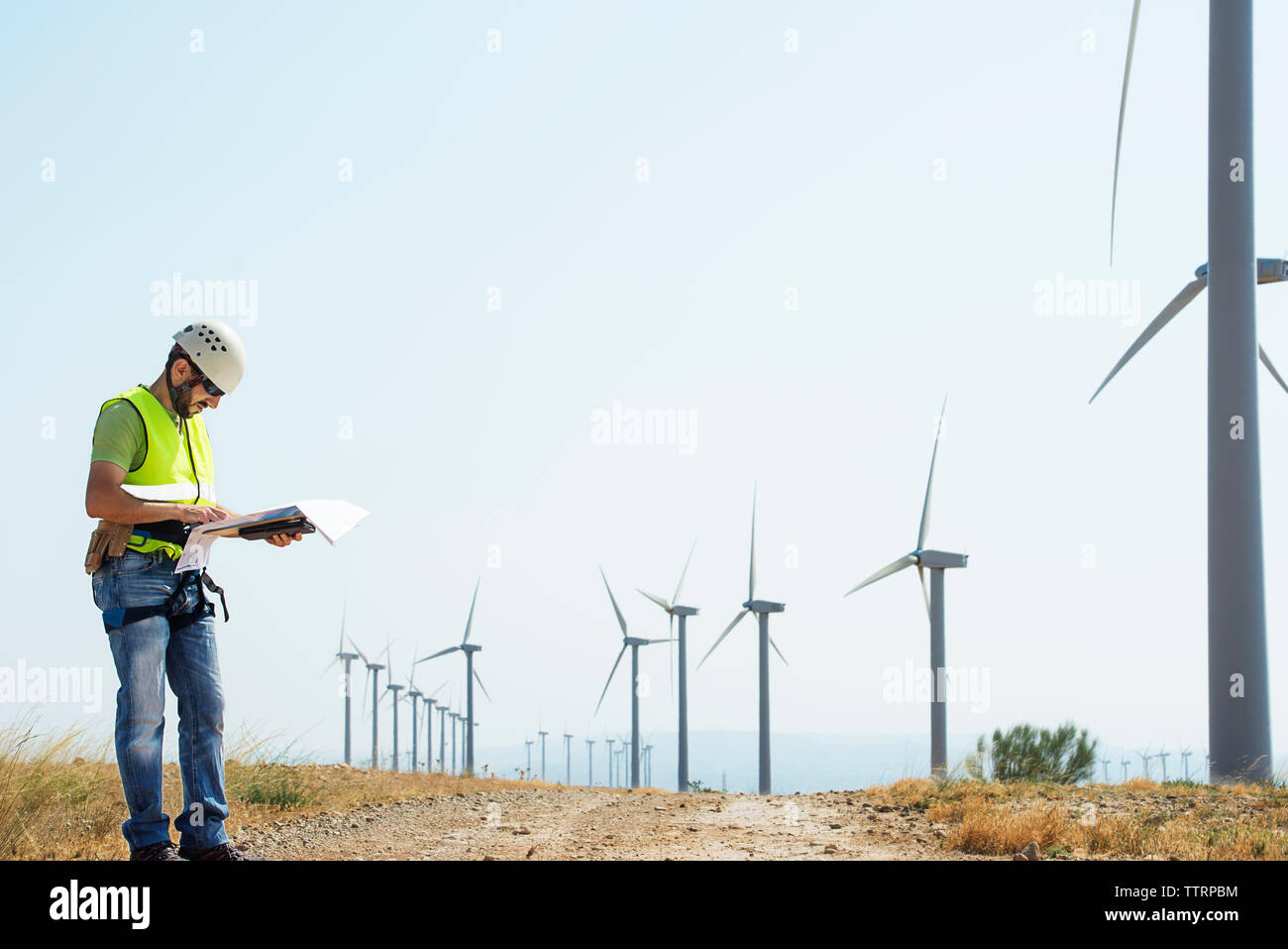 Engineer reading documents at wind farm against sky Stock Photo