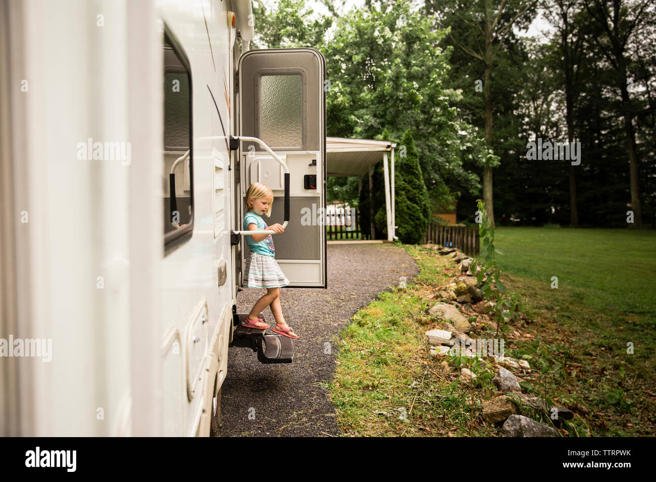 Girl moving down from steps of motor home Stock Photo