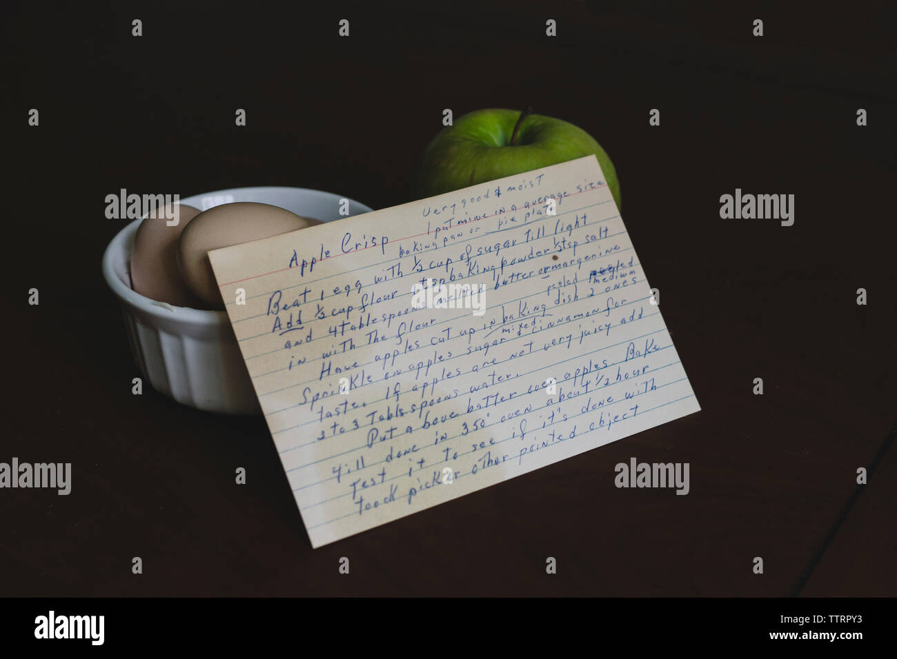 High angle view of recipe with eggs and granny smith apple over black background Stock Photo
