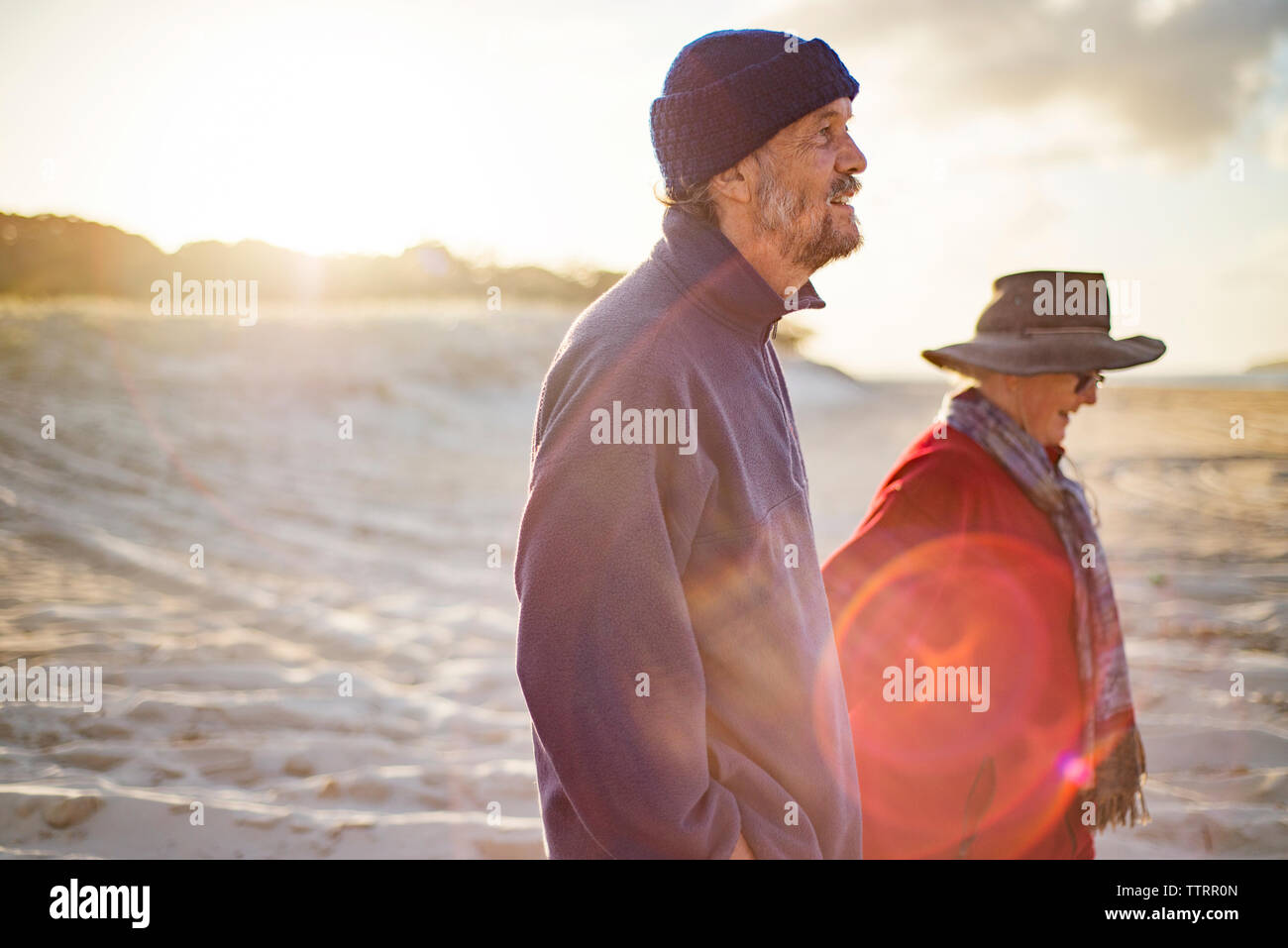 Happy senior couple walking at beach on sunny day Stock Photo