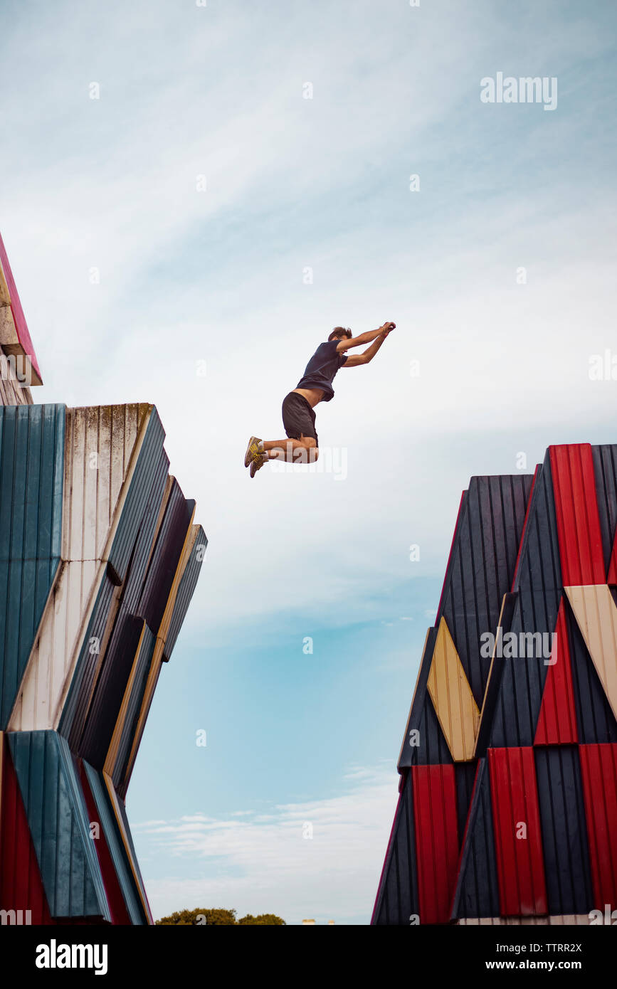Low angle view of man jumping over buildings against sky Stock Photo