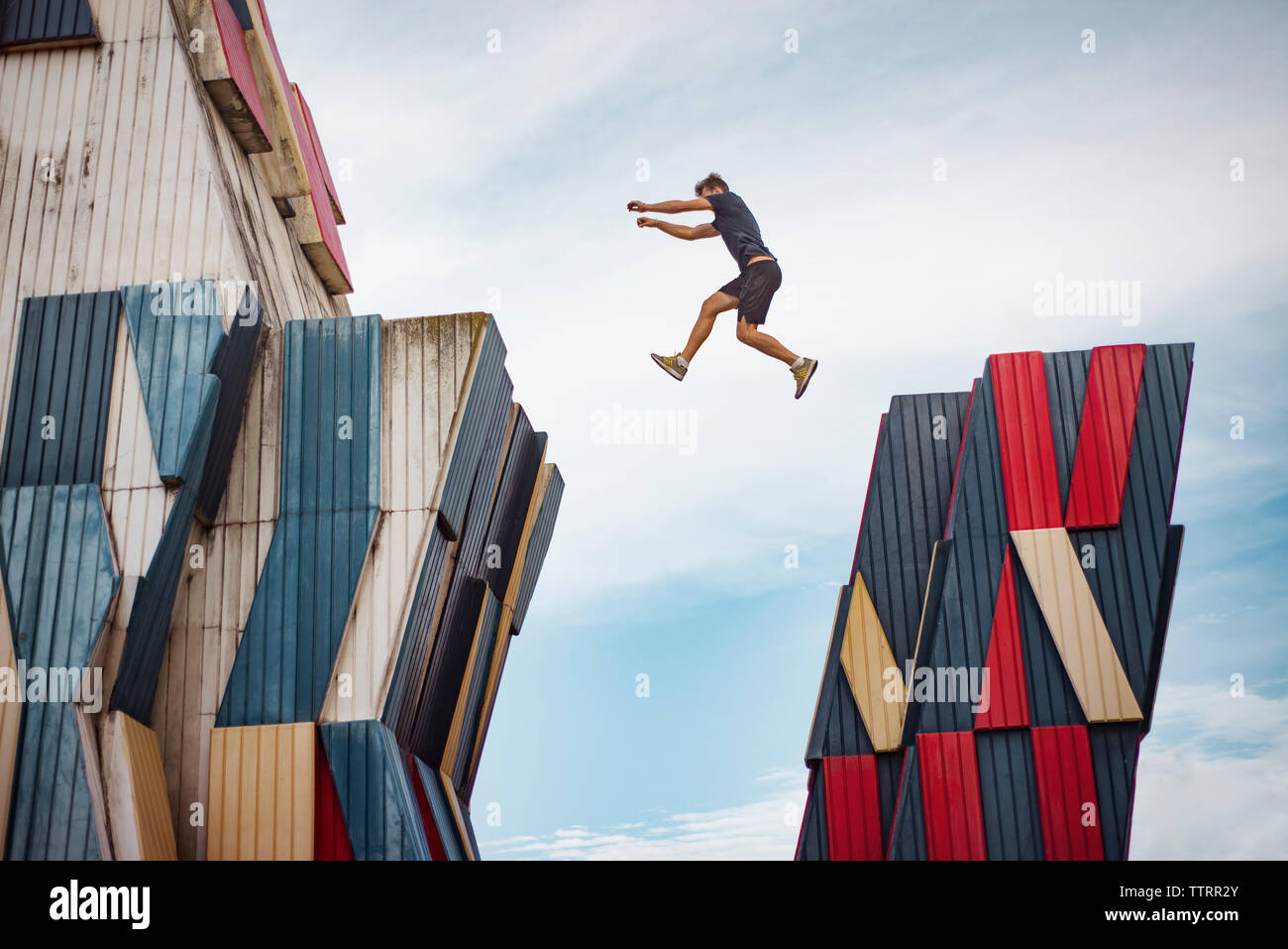 Low angle view of man jumping over buildings against sky Stock Photo