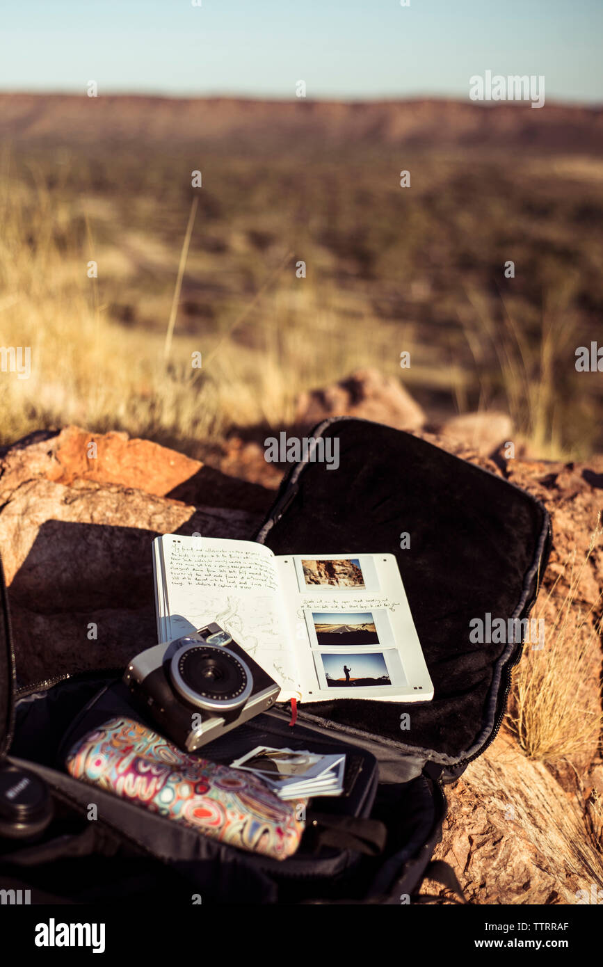 High angle view of camera with personal accessories on rock during sunny day Stock Photo