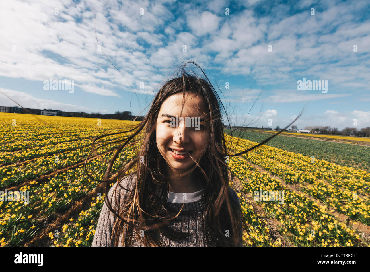 Wind blowing in long hair of woman standing on country field. Stock Photo