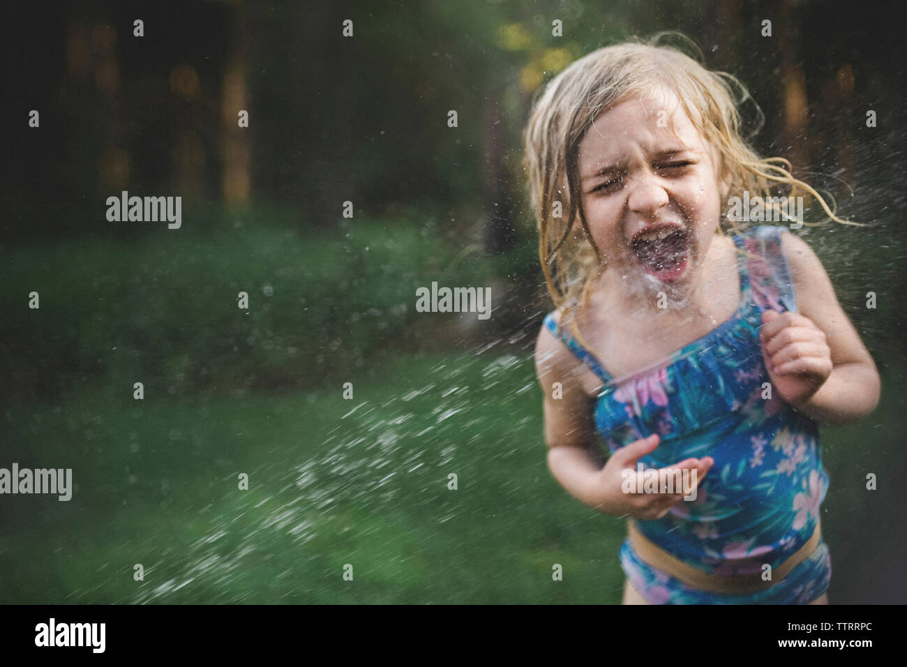 Girl enjoying in water spray at backyard Stock Photo