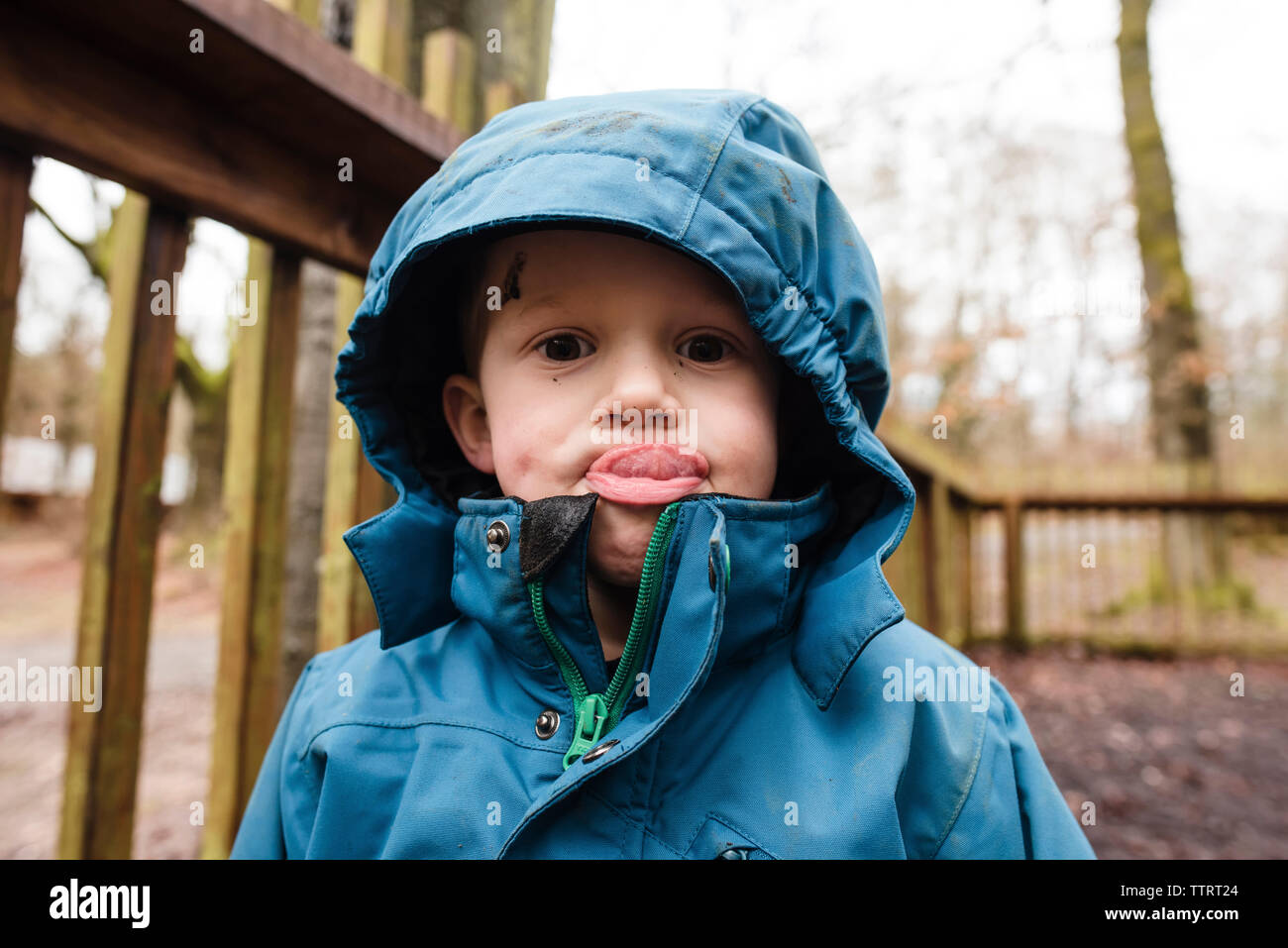 Portrait of boy sticking out tongue while standing at park Stock Photo