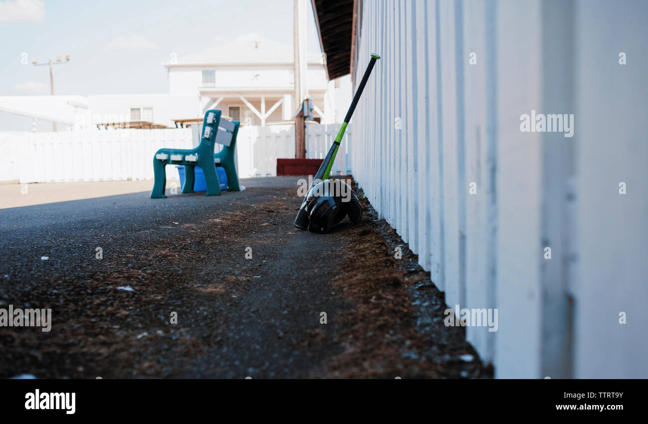Baseball bat and sports helmet against fence at playing field Stock Photo