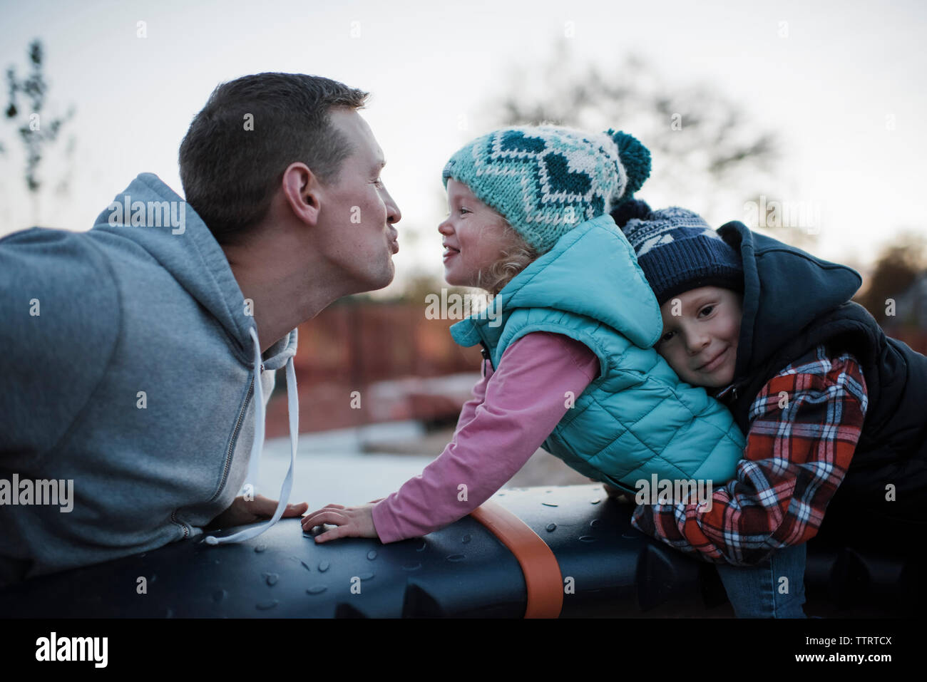 Portrait of brother holding sister playing with father at playground Stock Photo