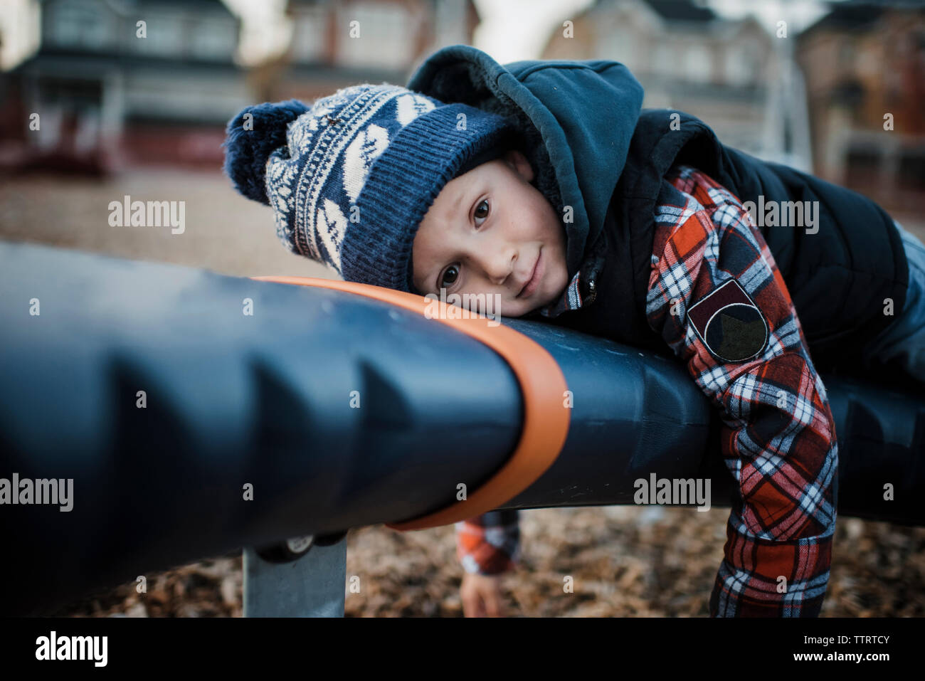 Portrait of cute boy lying on outdoor play equipment at playground Stock Photo