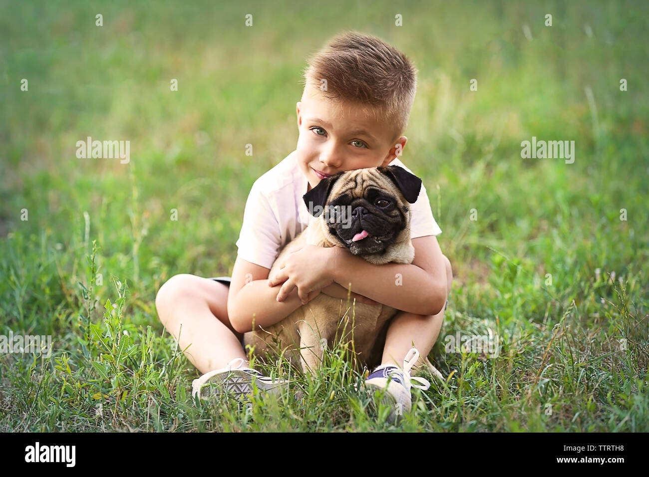 Cute boy with pug dog on green grass Stock Photo - Alamy