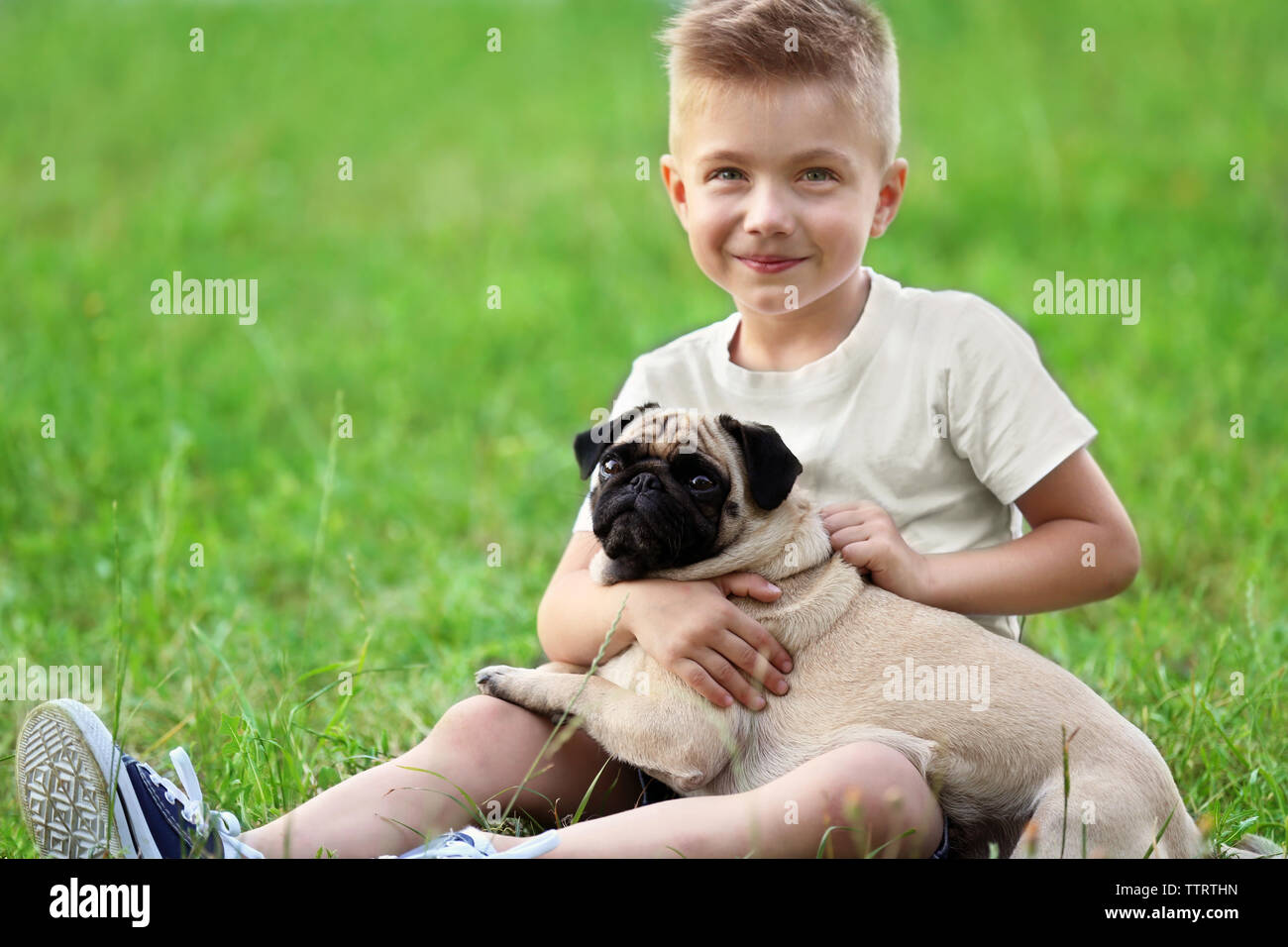 Cute boy with pug dog on green grass Stock Photo - Alamy