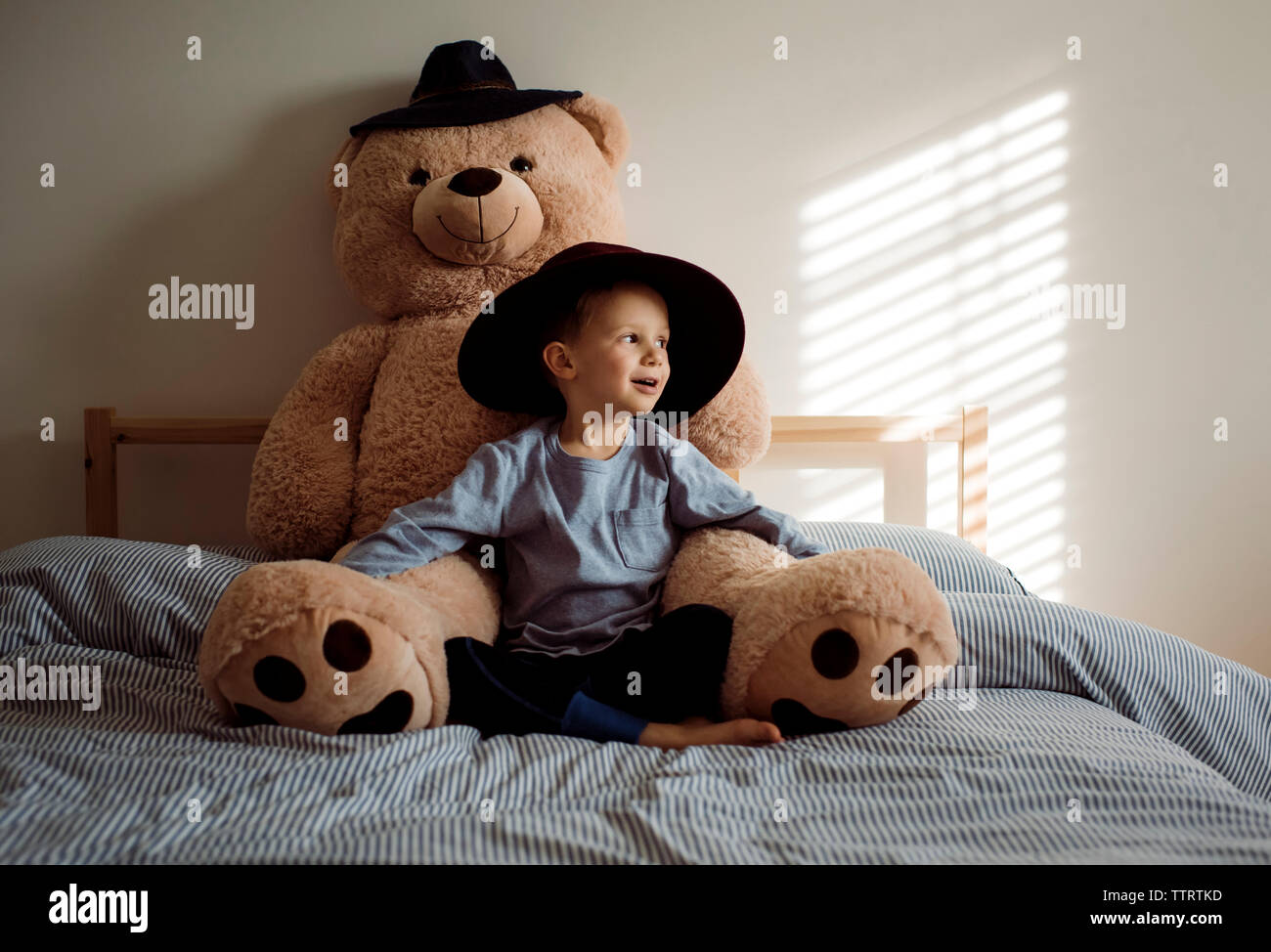 Boy with teddy bear sitting on bed at home Stock Photo - Alamy