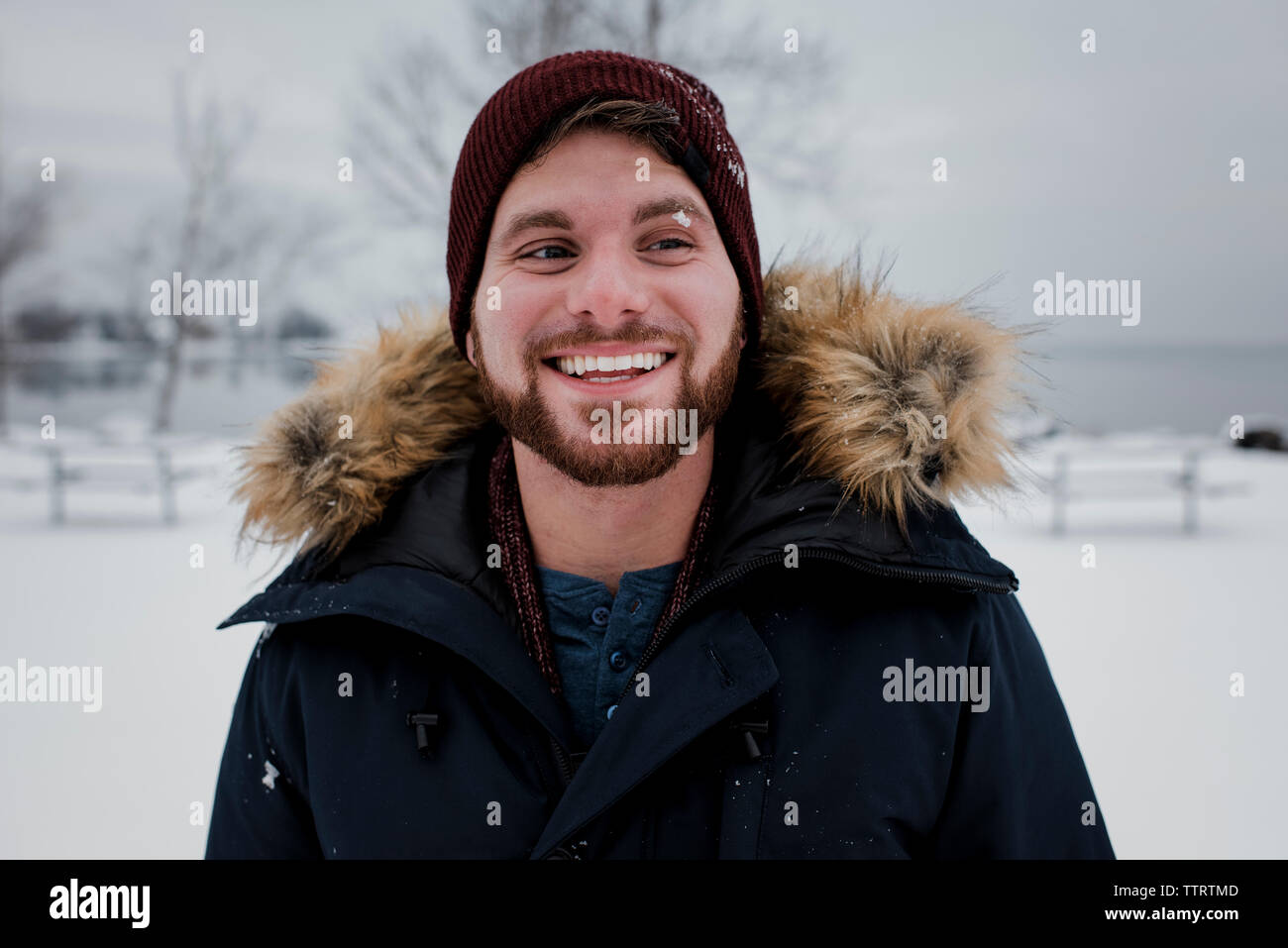 Smiling man looking away while standing against sky during winter Stock Photo