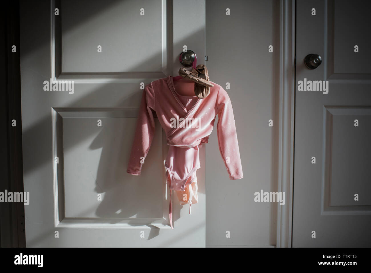 Ballet costume with shoes hanging on door knob at home Stock Photo