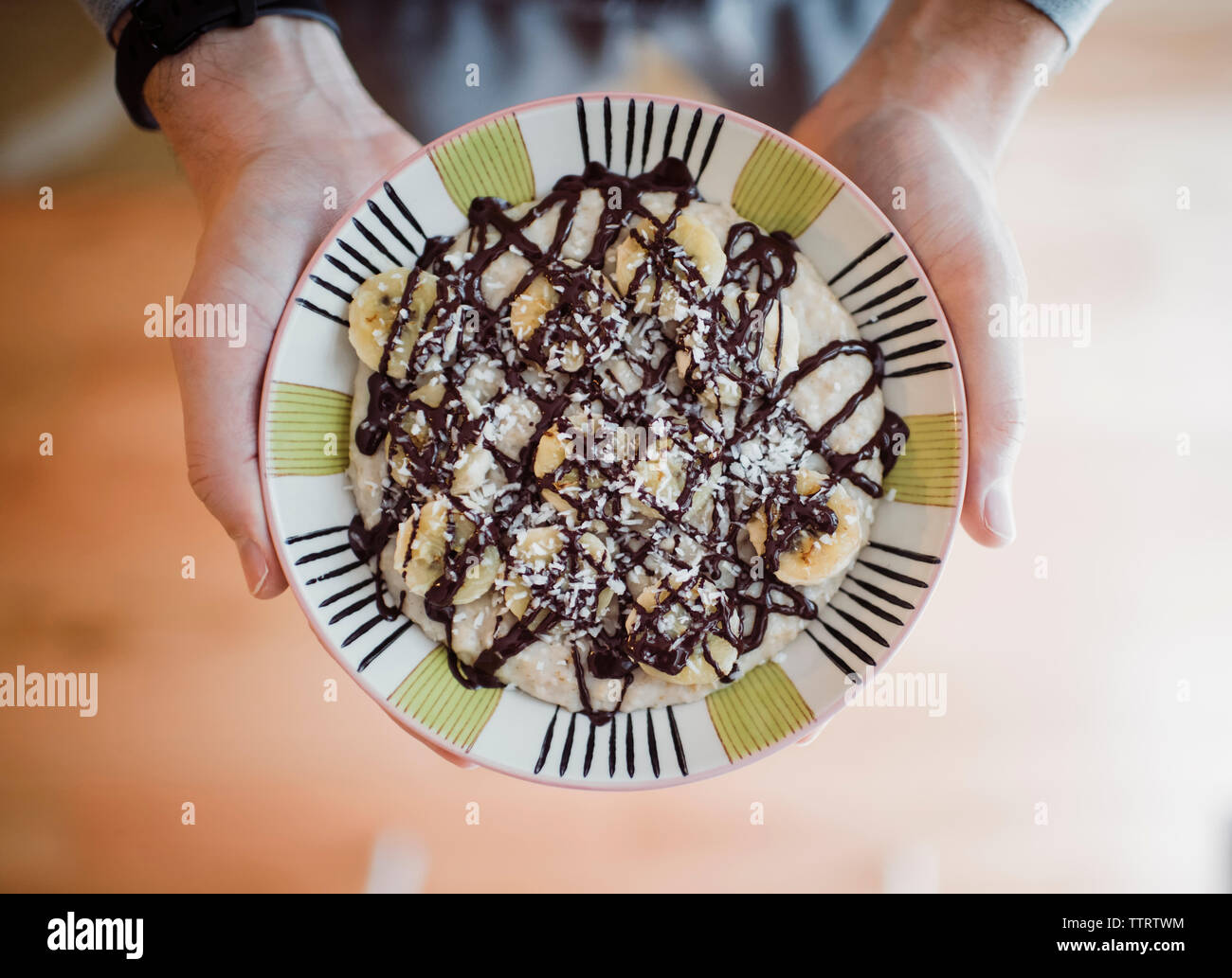 Cropped hands of man holding pancake with banana slices and chocolate sauce in plate Stock Photo