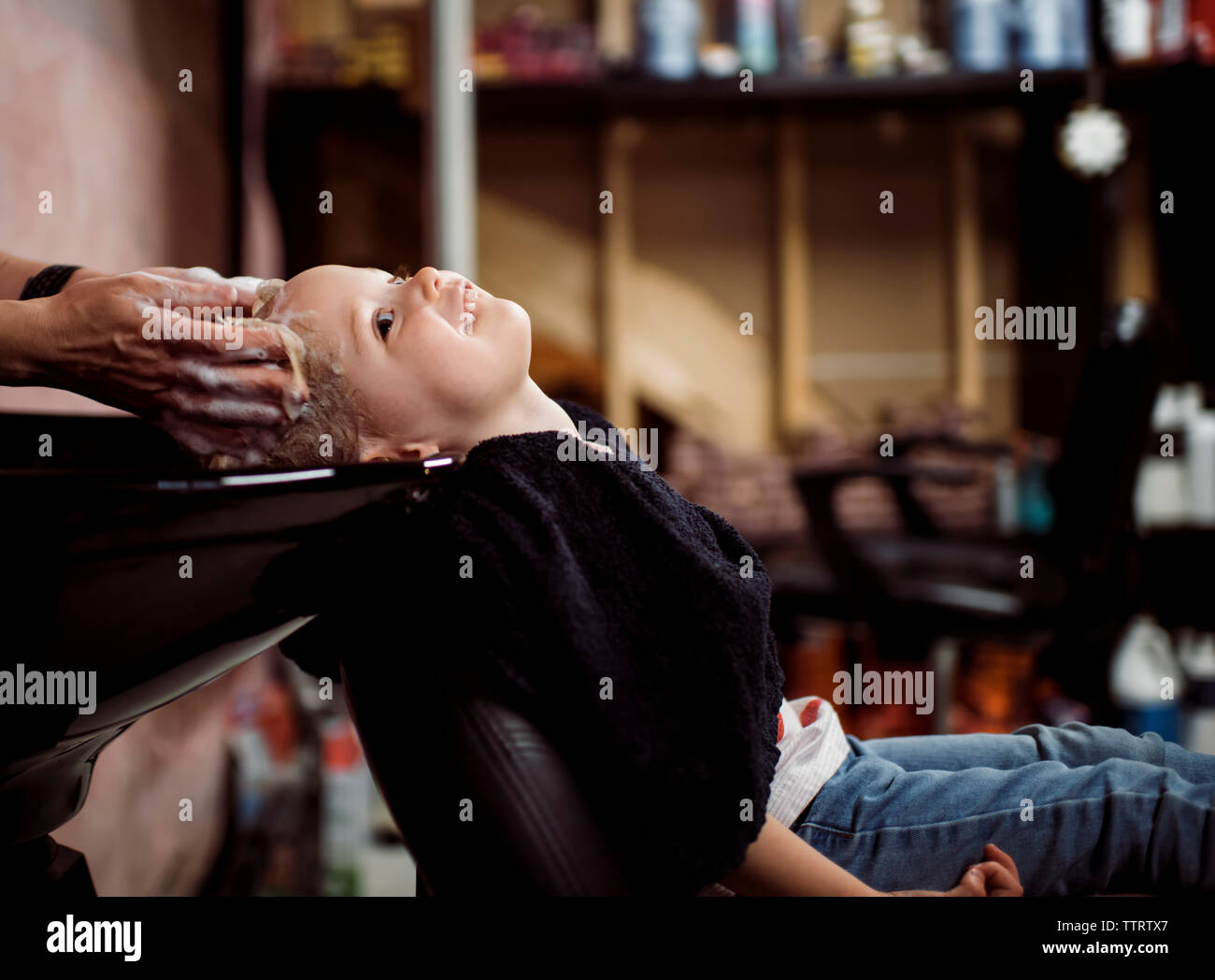 Cropped hands of hairdresser washing girl's hair in salon Stock Photo