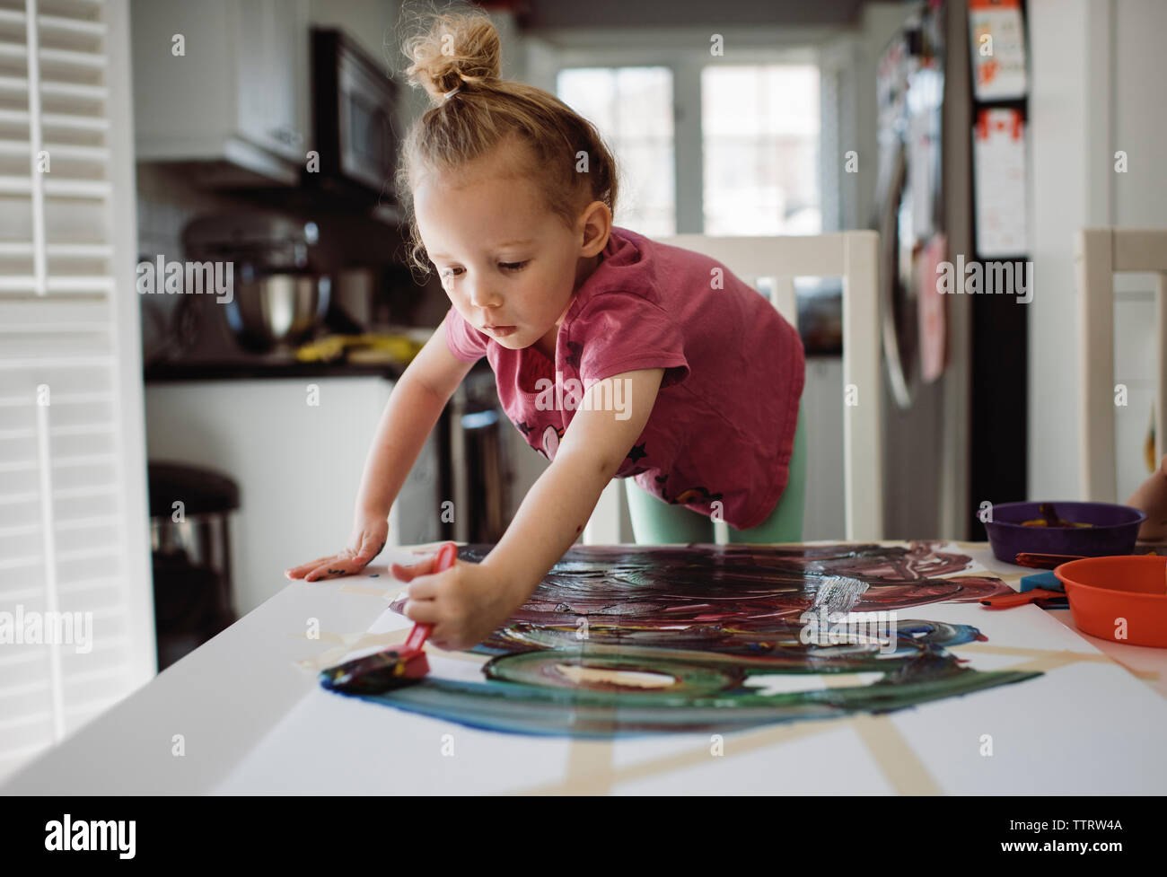 Girl painting on paper while standing by table at home Stock Photo