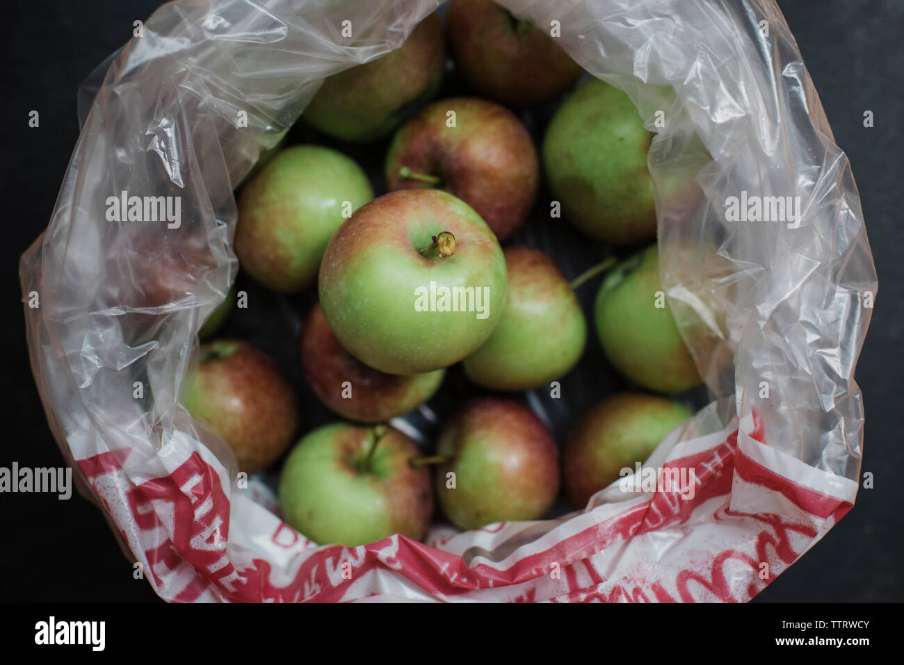 Overhead view of fresh harvested apples in plastic bag on table Stock Photo