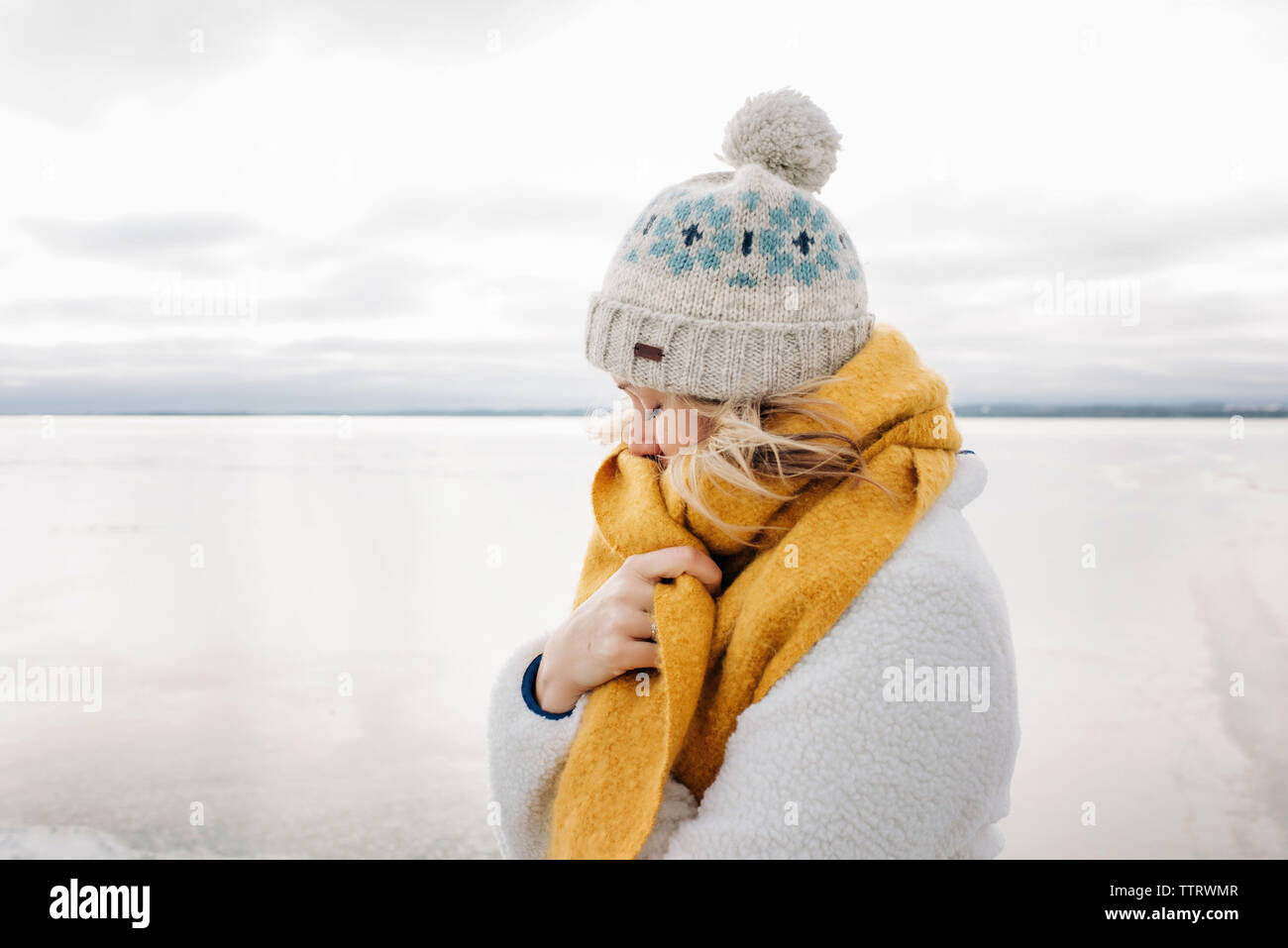 portrait of blonde woman keeping warm at the beach in winter thinking Stock Photo