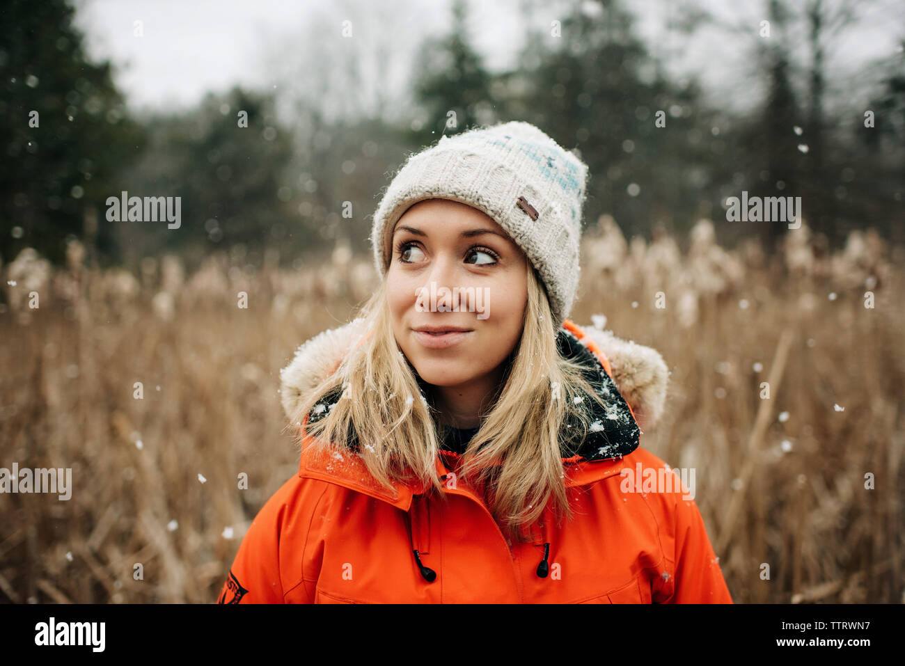 woman smiling standing in the snow with winter coat and hat Stock Photo