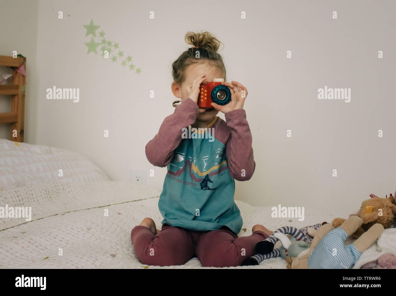 young girl holding camera playing in her bedroom taking pictures Stock Photo