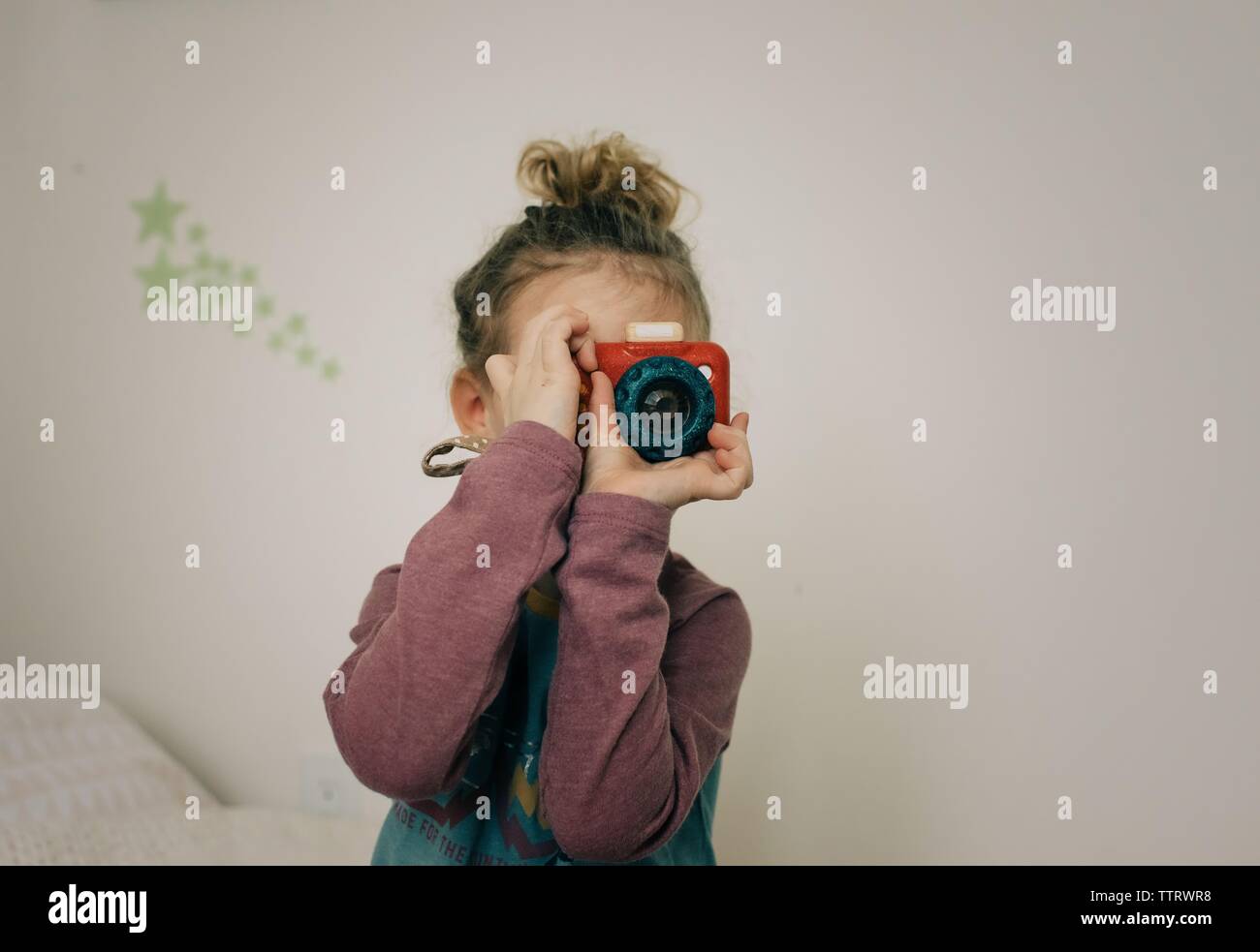 young blonde girl holding camera taking pictures in here bedroom Stock Photo