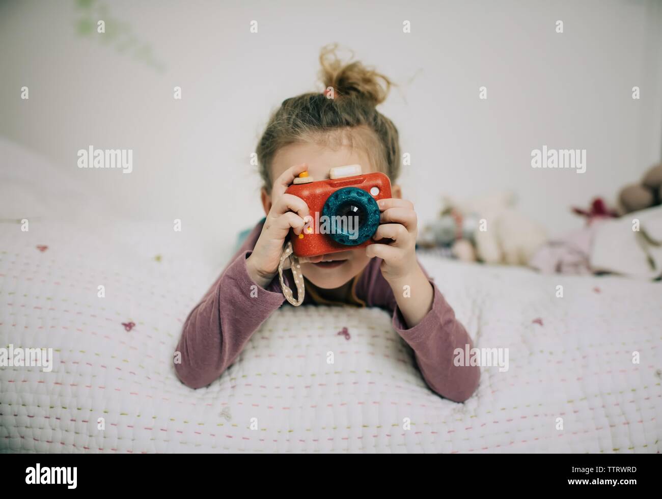 girl holding up a camera to her face taking pictures in her bedroom Stock Photo