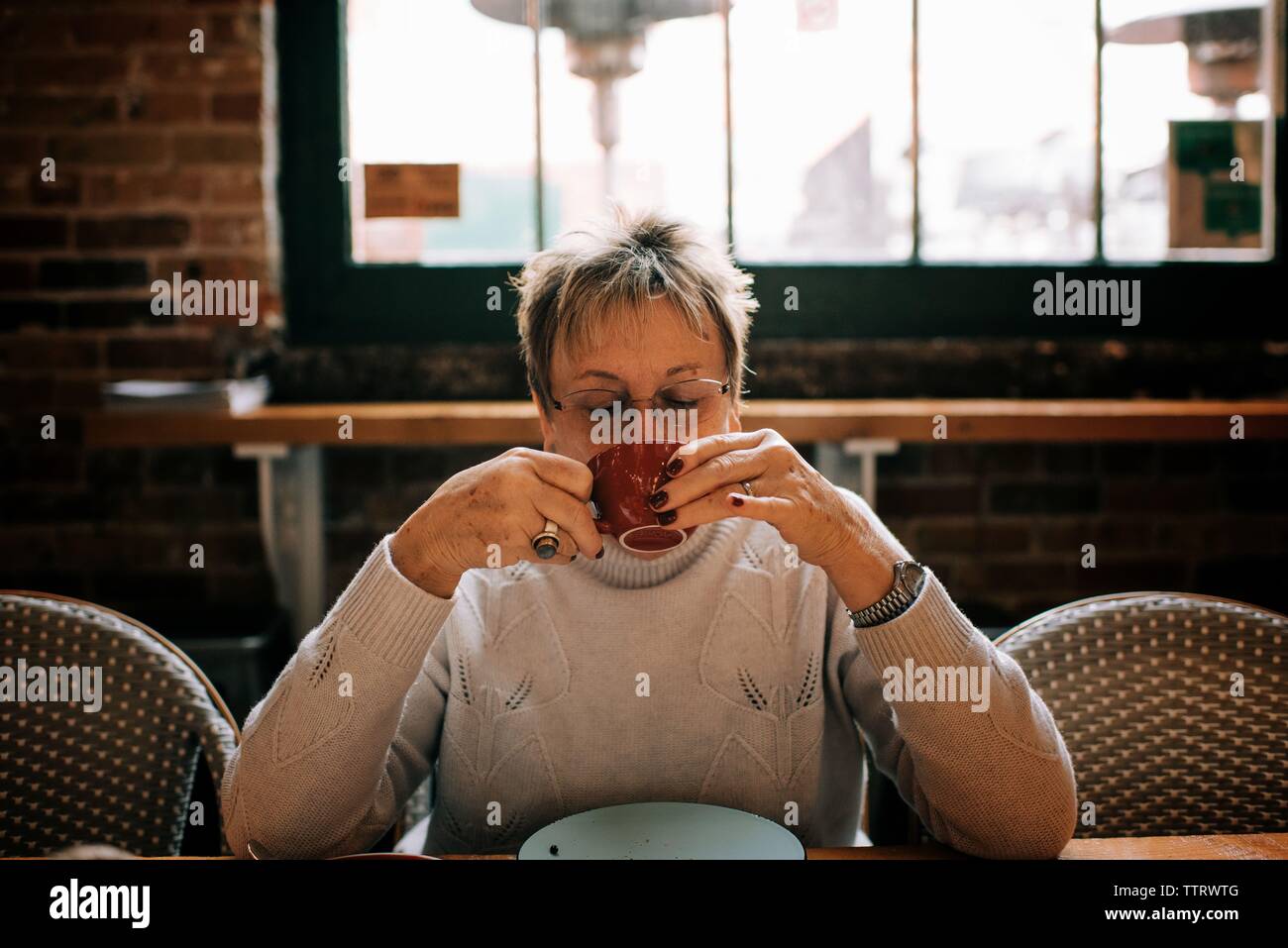 woman in her 60's drinking a cup of coffee in a cafe Stock Photo