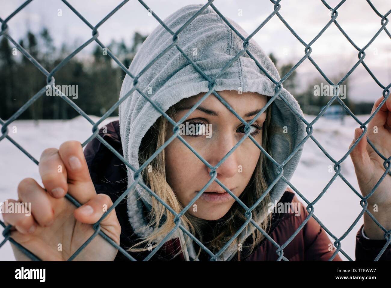 portrait of woman looking through a metal fence looking at the camera Stock Photo