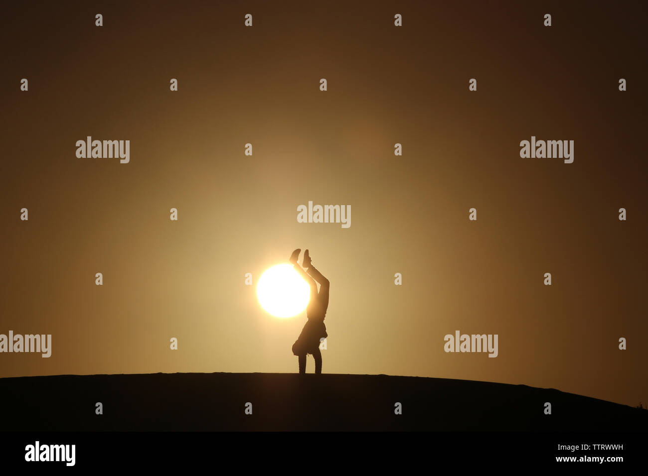 Silhouette man doing handstand on field against clear sky during sunset Stock Photo