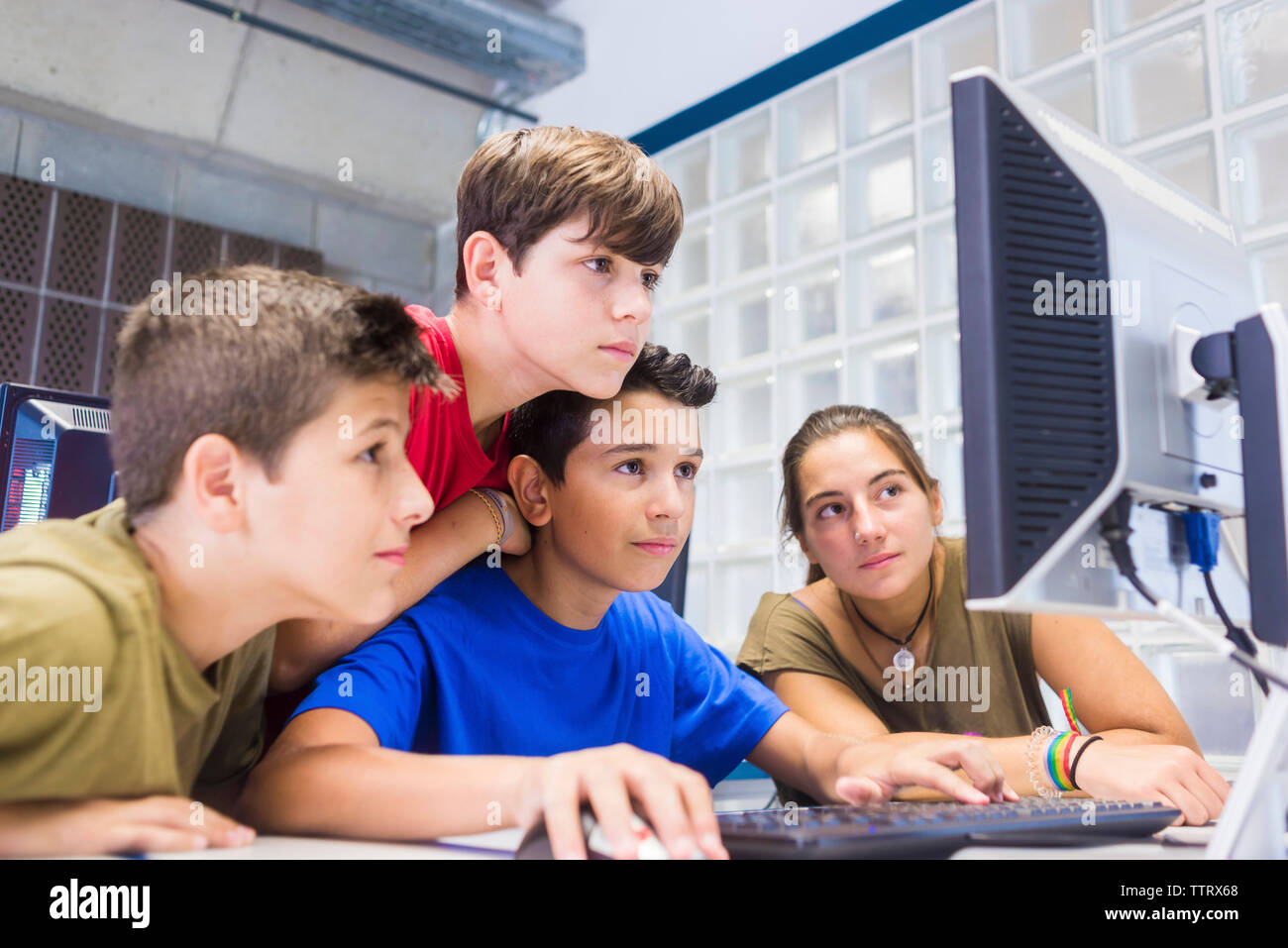Teacher teaching students over desktop computer in classroom Stock