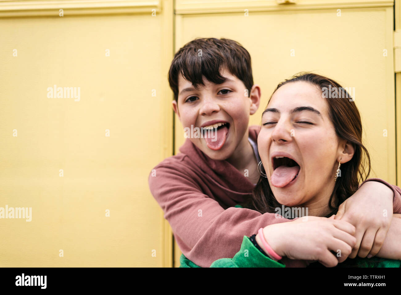 Portrait of teenagers showing the tongue while sitting outdoors Stock Photo