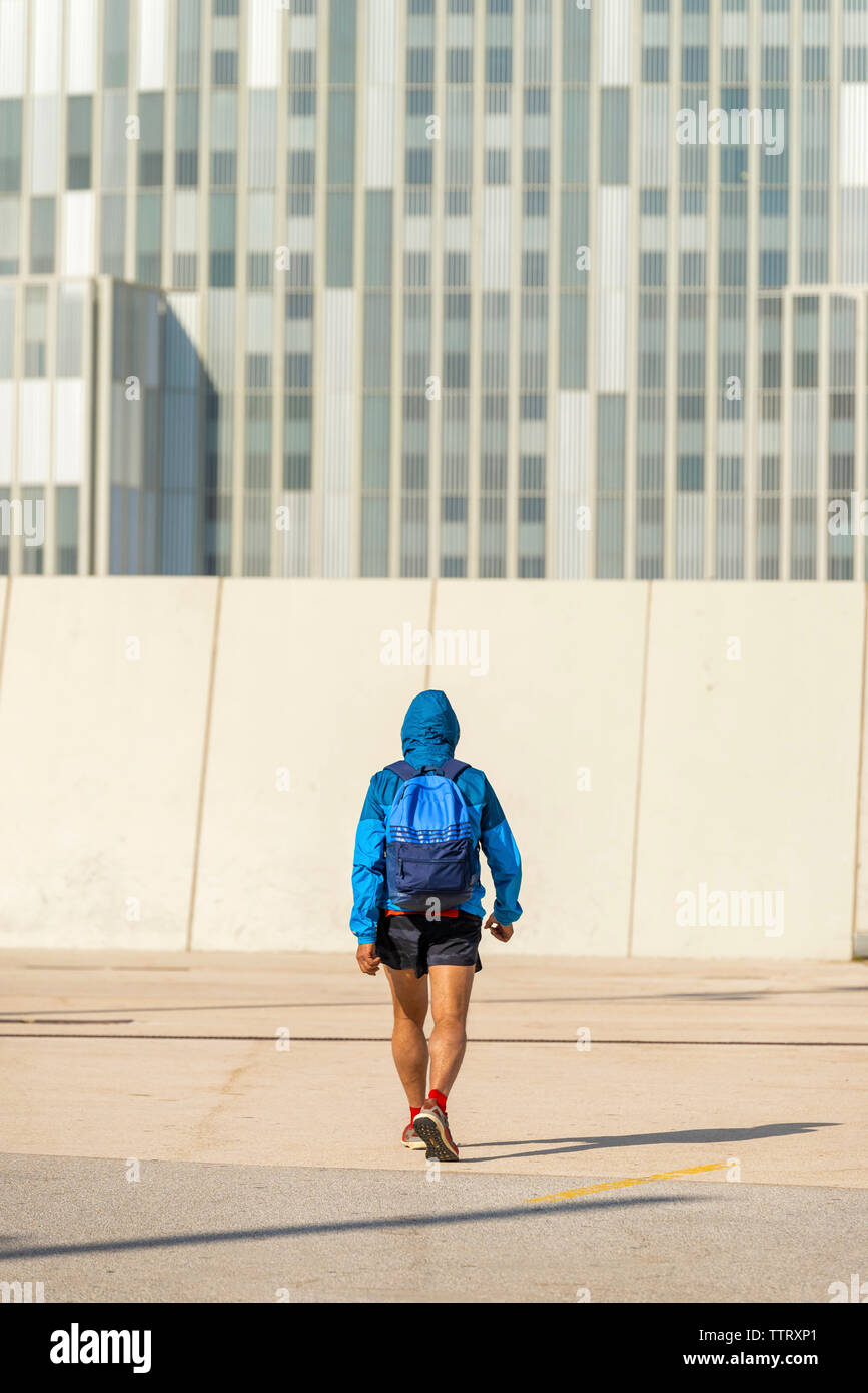 Rear view of senior sport man wearing hoodie and backpack walking away Stock Photo