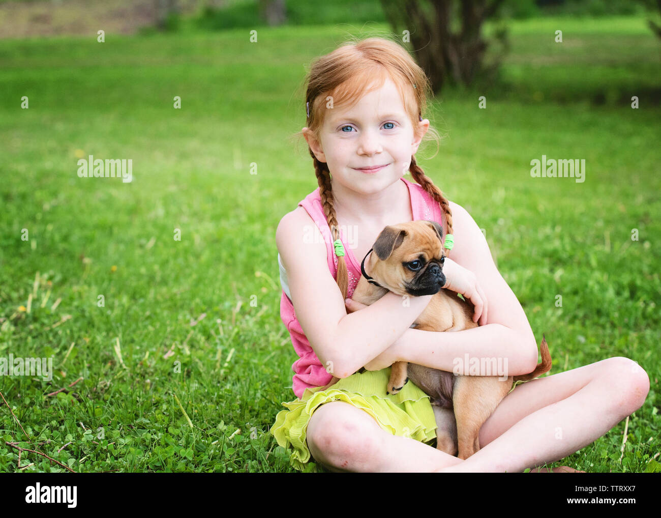 Portrait of cute girl with puppy sitting at park Stock Photo