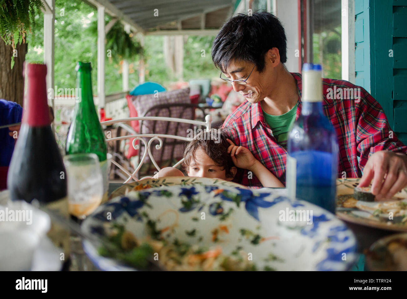 Father and son having lunch at dining table on porch Stock Photo