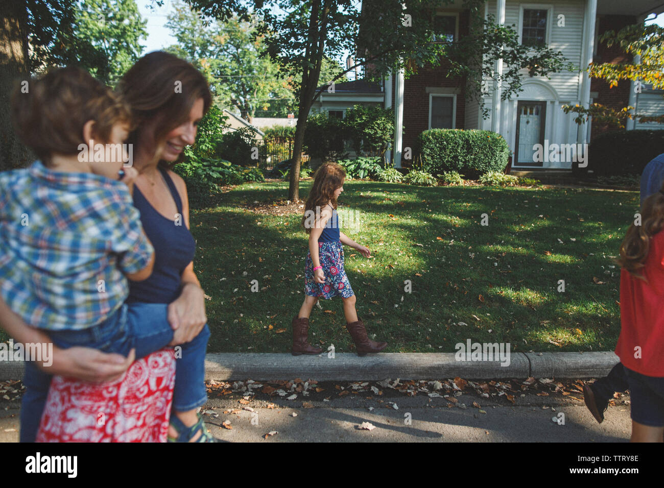 Mother with children walking on road at yard Stock Photo