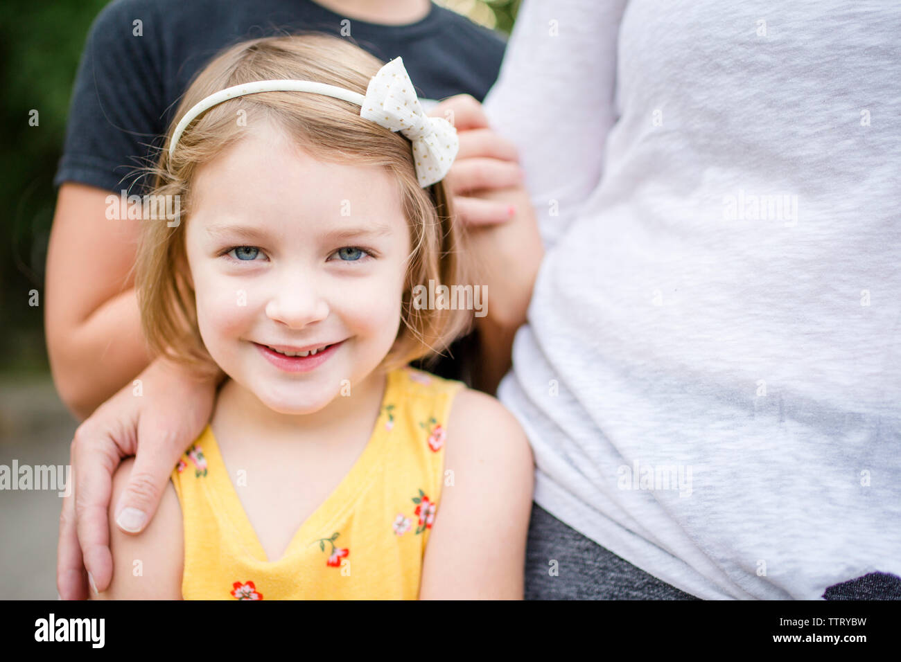 Portrait of cute girl standing with family in yard Stock Photo