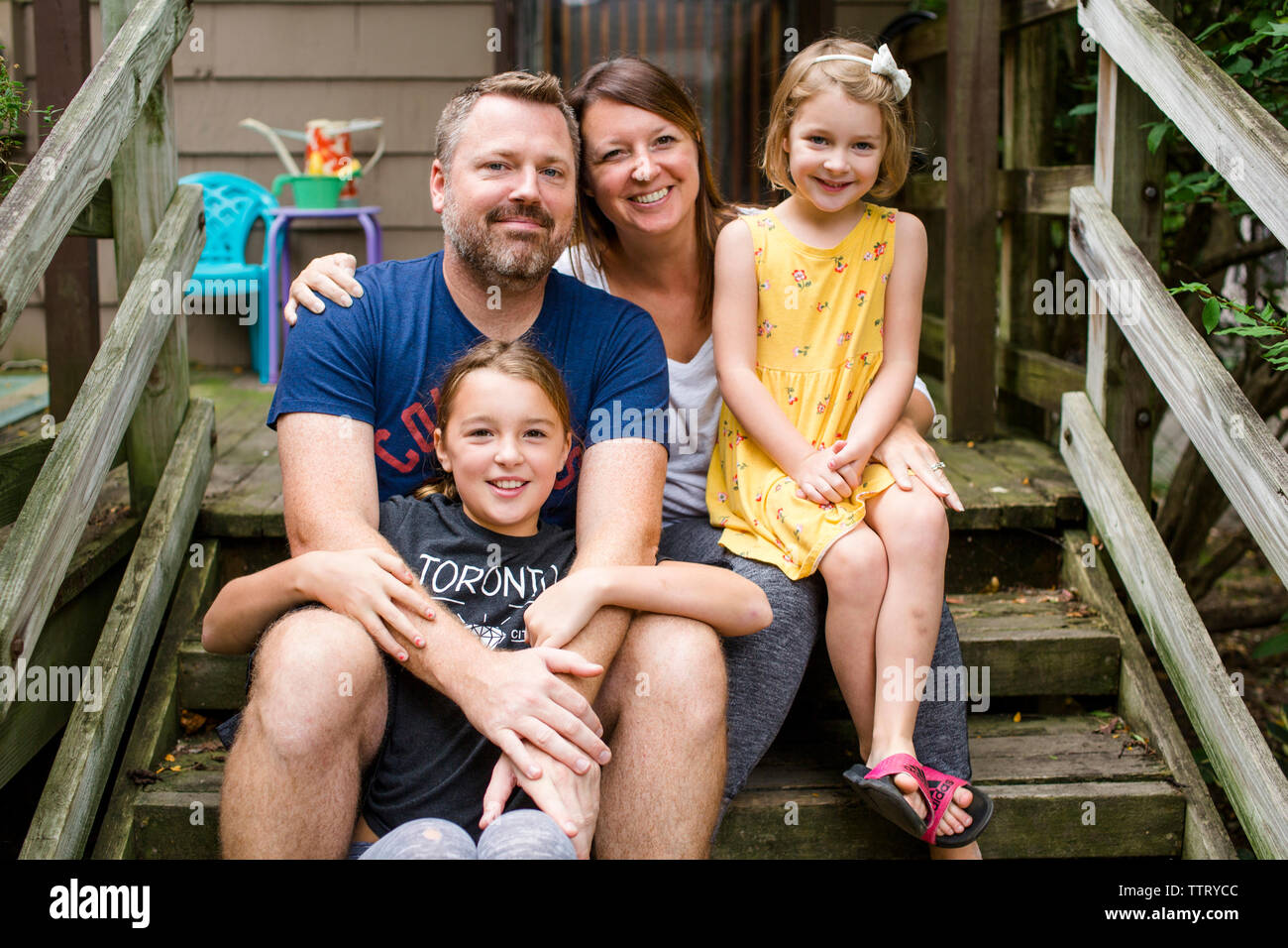 Portrait of happy family sitting on steps against house in yard Stock Photo