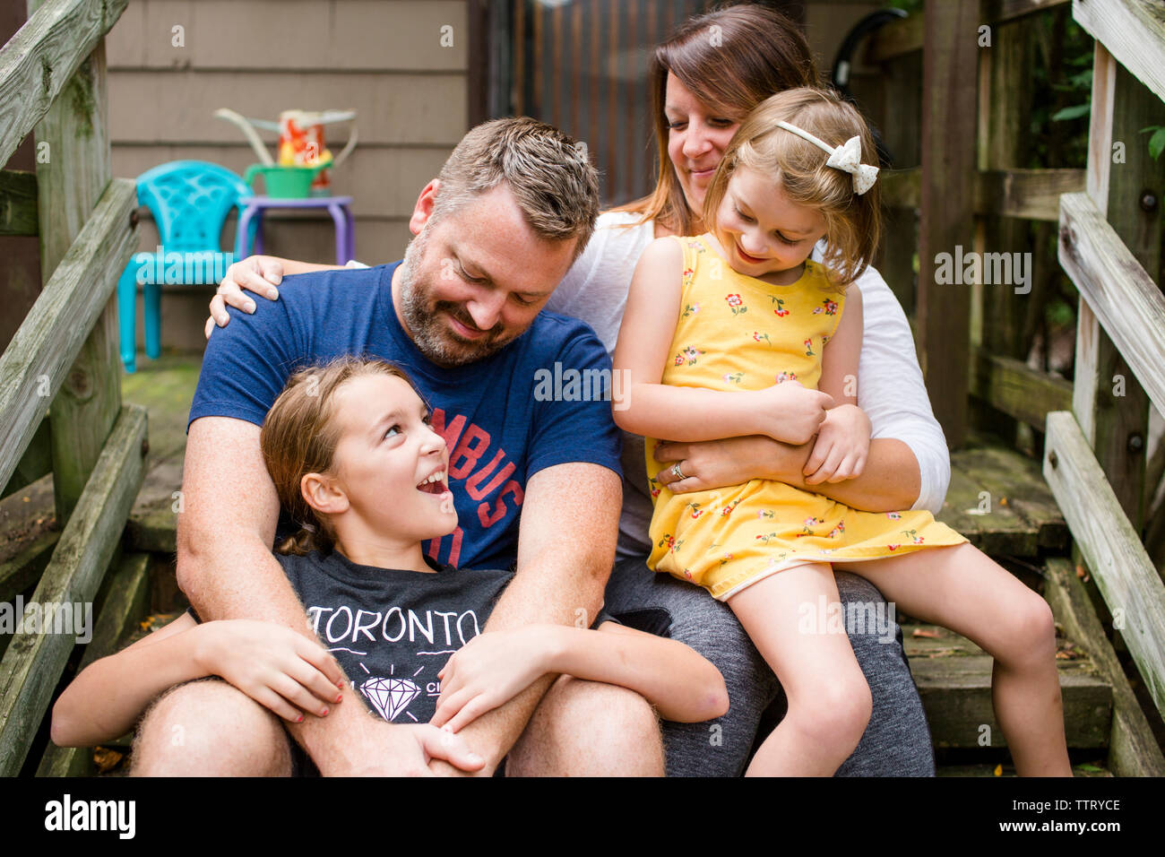 Happy family sitting on steps against house in yard Stock Photo