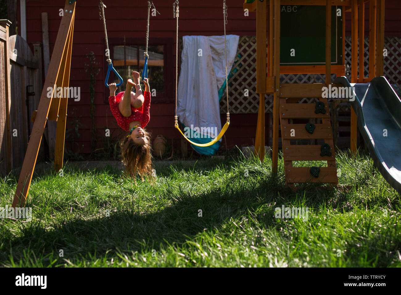 Playful girl hanging upside down at playground Stock Photo - Alamy