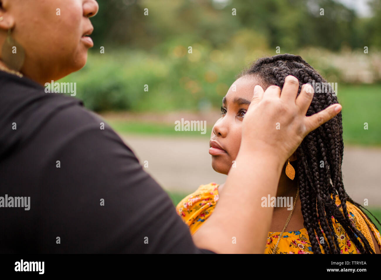 Midsection of mother with hand in daughter's hair standing at park Stock Photo