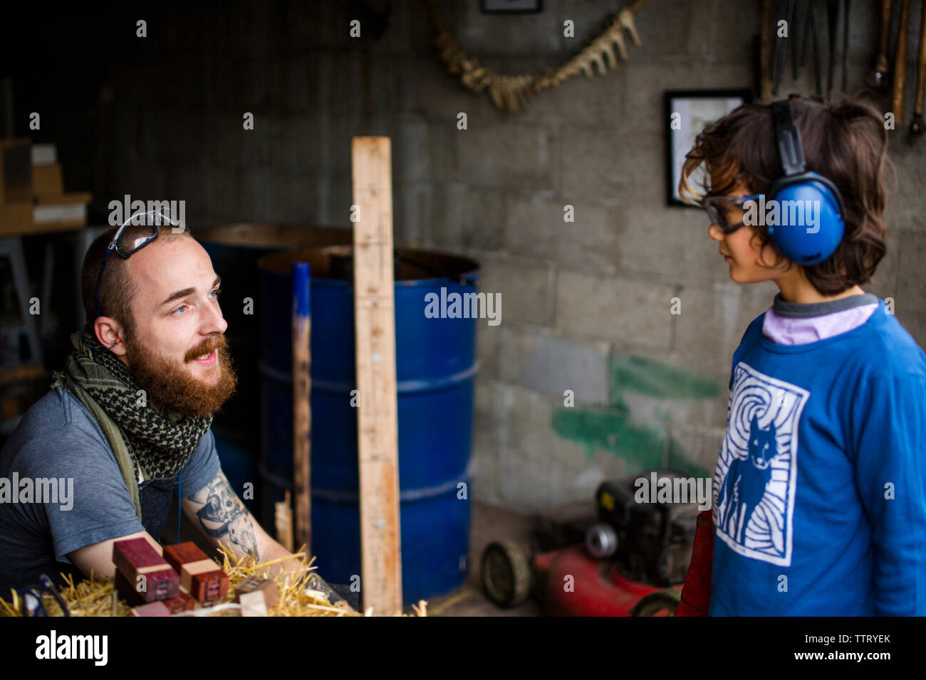 High angle view of blacksmith talking to boy in workshop Stock Photo